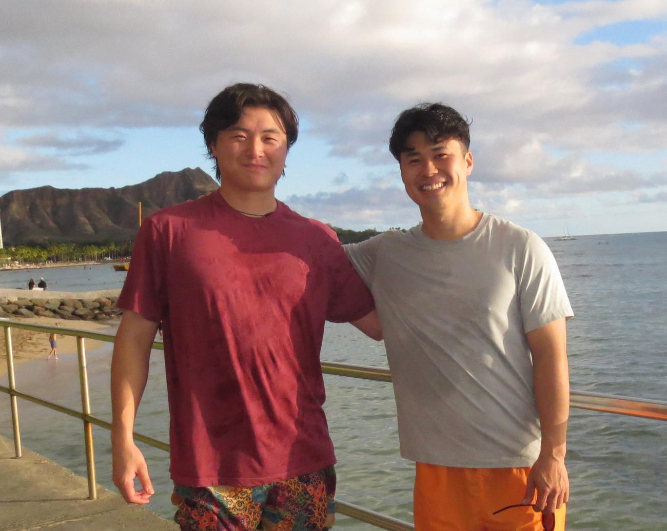 ワイキキの海を背に肩を組むソフトバンク前田純（左）と松本晴（撮影・佐藤究）