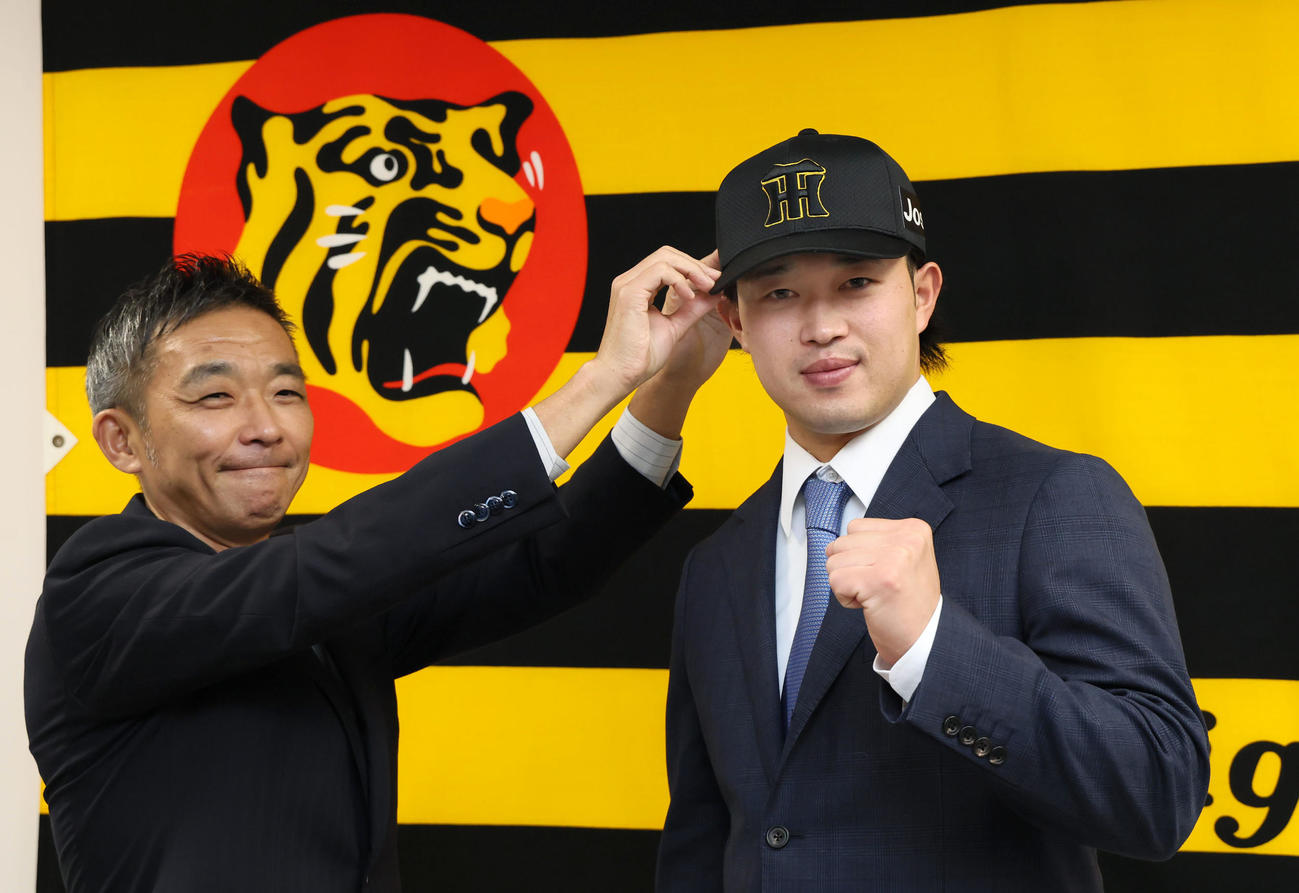 ヤクルトから現役ドラフトで加入した浜田（右）は竹内副本部長から帽子をかぶせてもらう（撮影・加藤哉）