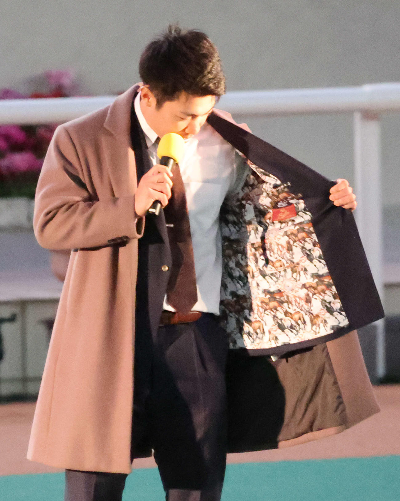 阪神競馬場の阪神JF終了後のパドックで行われたトークショーに出演した阪神石井はスーツの裏地を見せる（撮影・西尾就之）