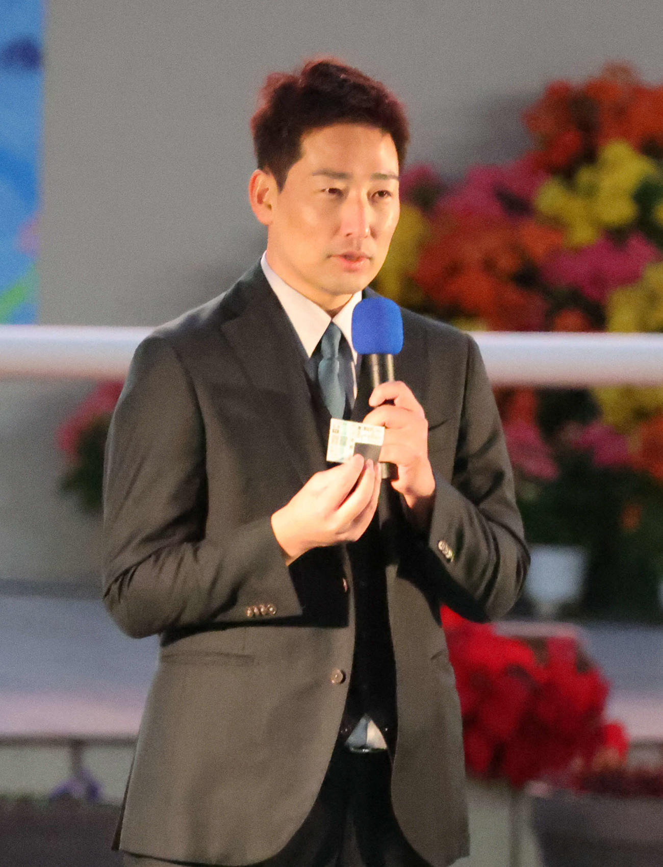 阪神競馬場の阪神JF終了後のパドックで行われたトークショーに出演した阪神岩崎は当たり馬券を見せる（撮影・西尾就之）