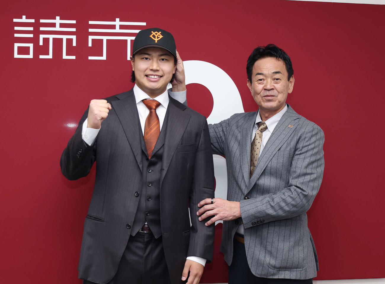 現役ドラフトで入団し水野編成副本部長（右）に帽子をかぶせてもらい笑顔を向ける松浦（撮影・増田悦実）