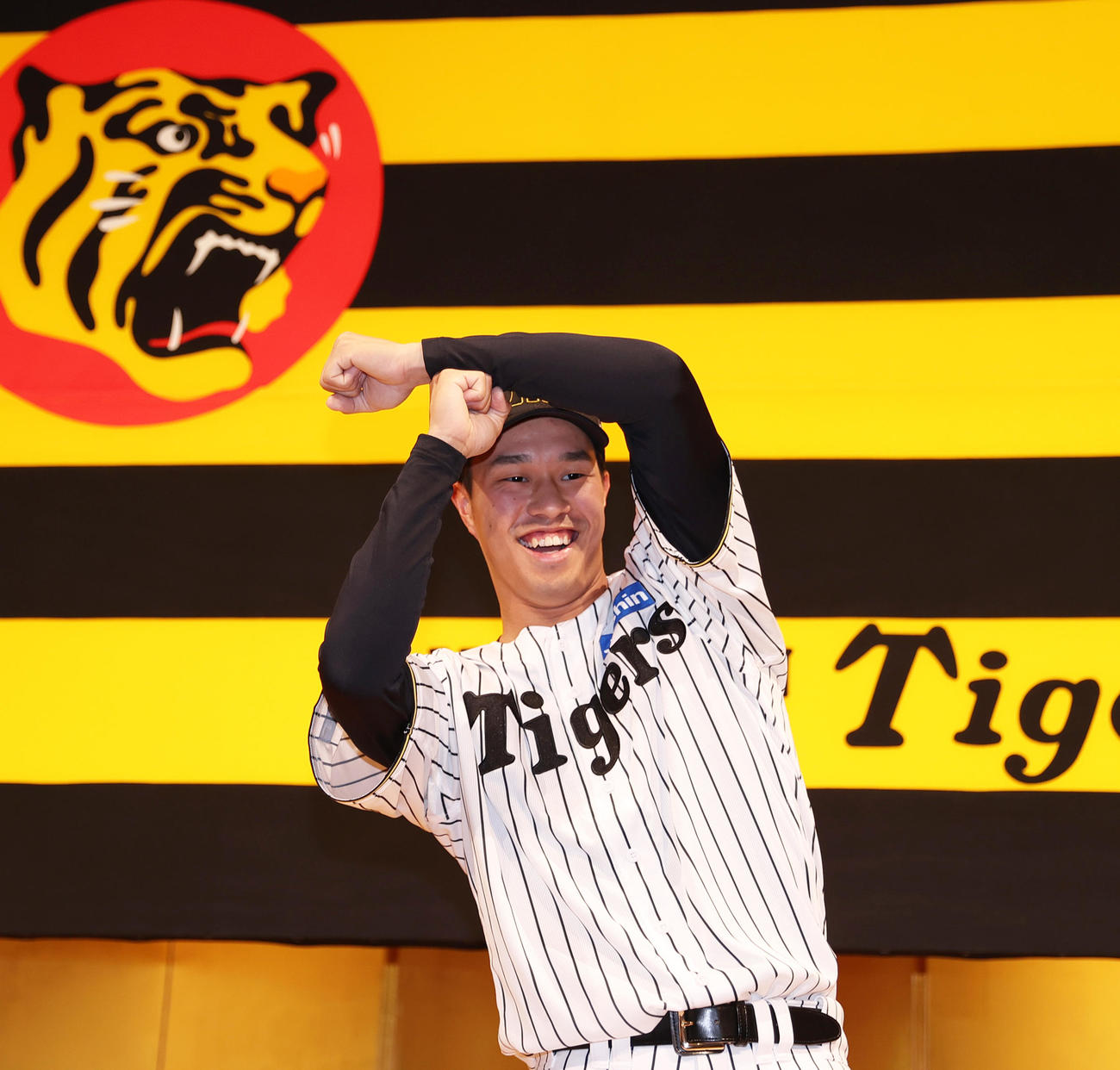 阪神新人入団会見でポーズをとるドラフト3位の岡城（撮影・上山淳一）
