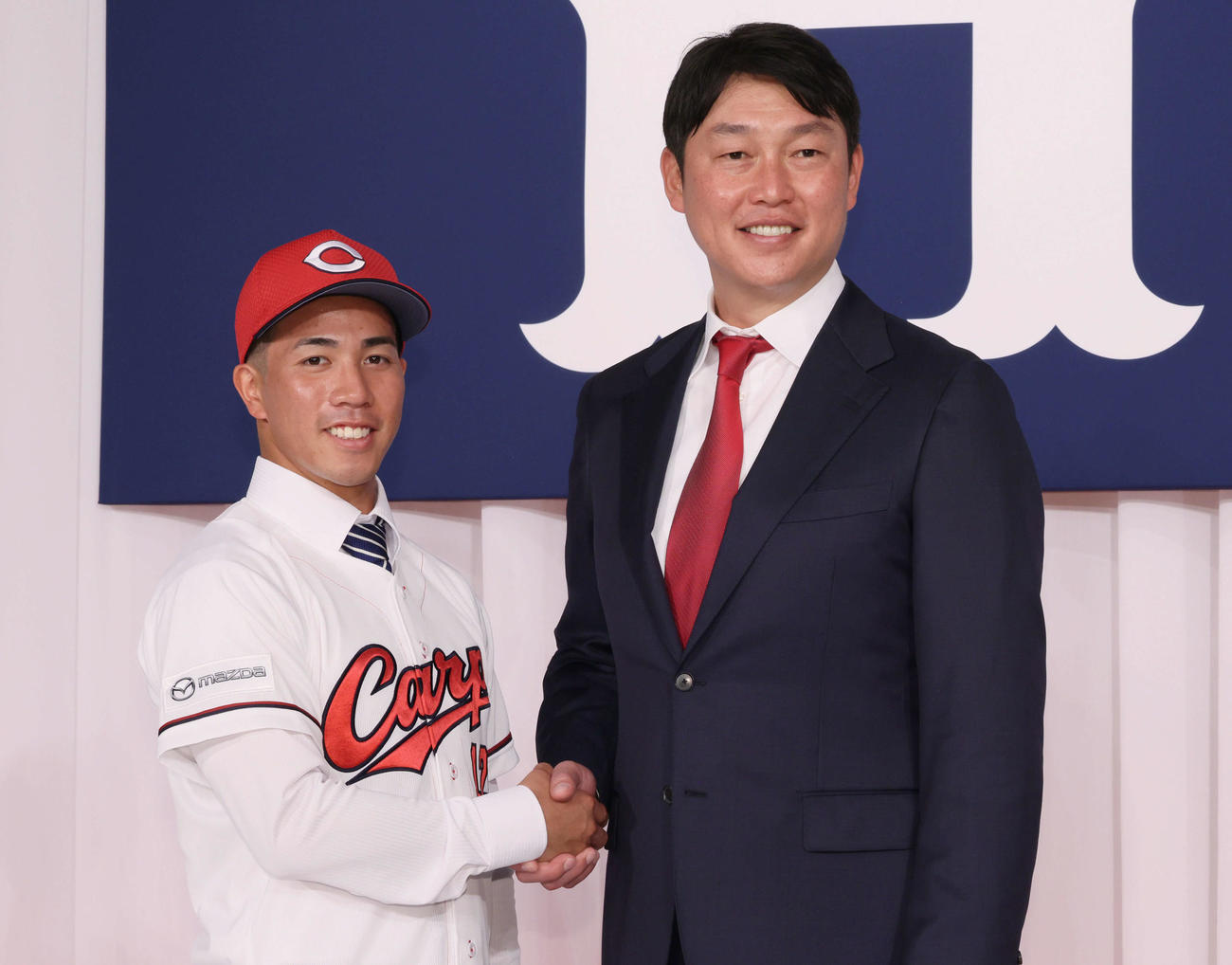 新井監督（右）と握手する育成2位の岸本（撮影・加藤孝規）