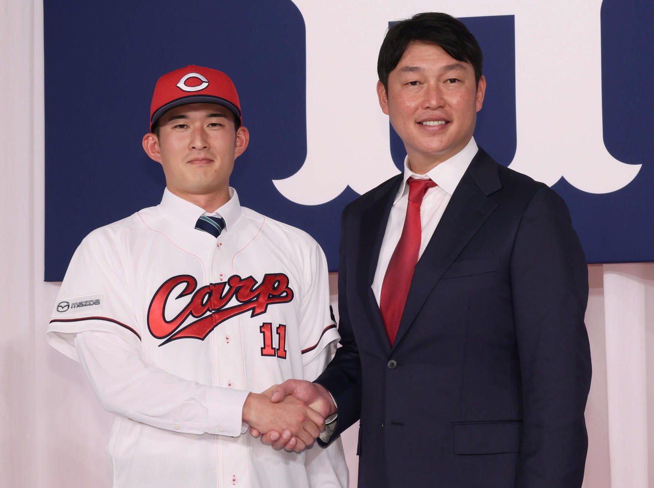 新井監督（右）と握手するドラフト2位の斉藤汰（撮影・加藤孝規）