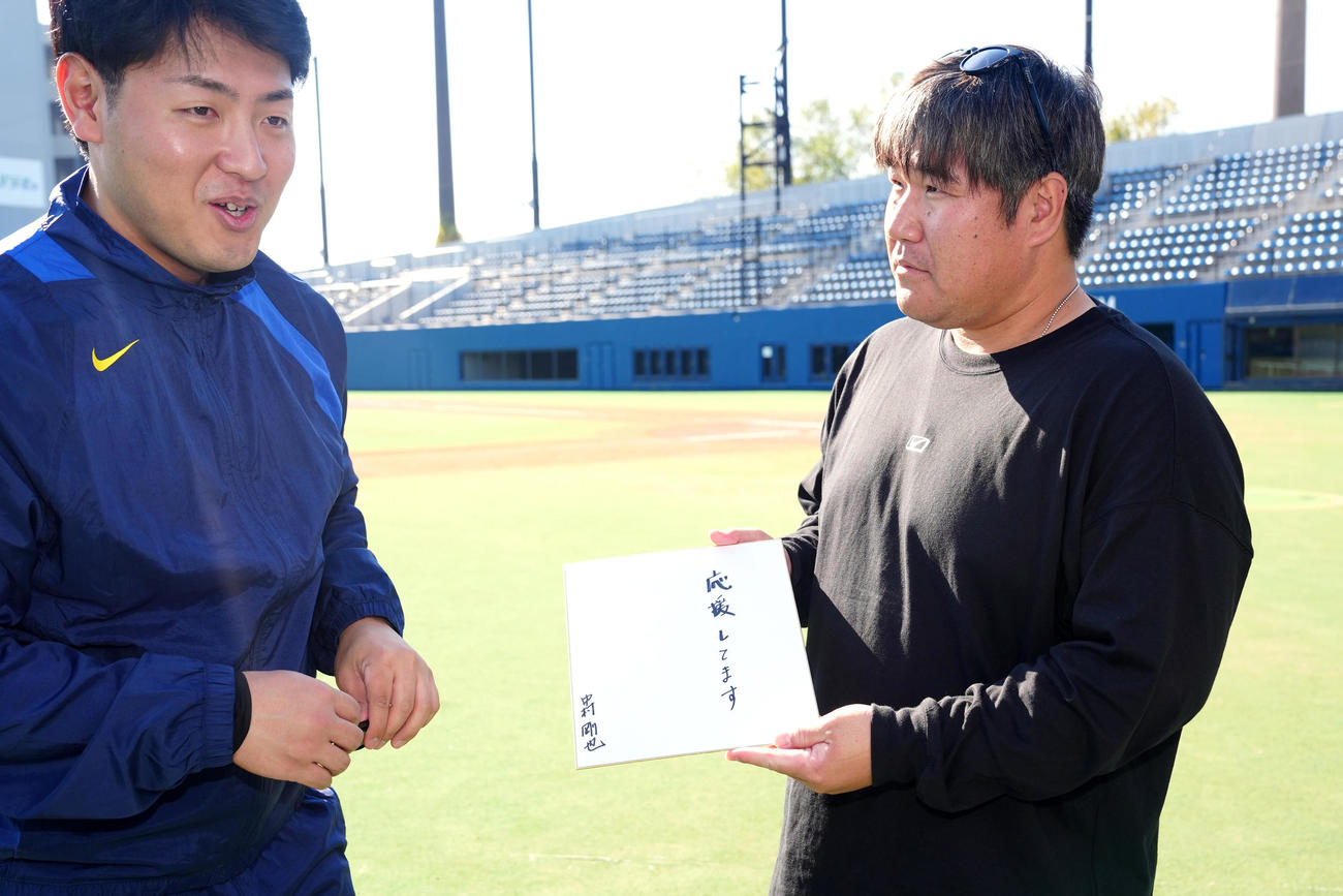 合同自主トレ後、「応援してます」と記した色紙を岡本（左）に渡す中村（撮影・江口和貴）
