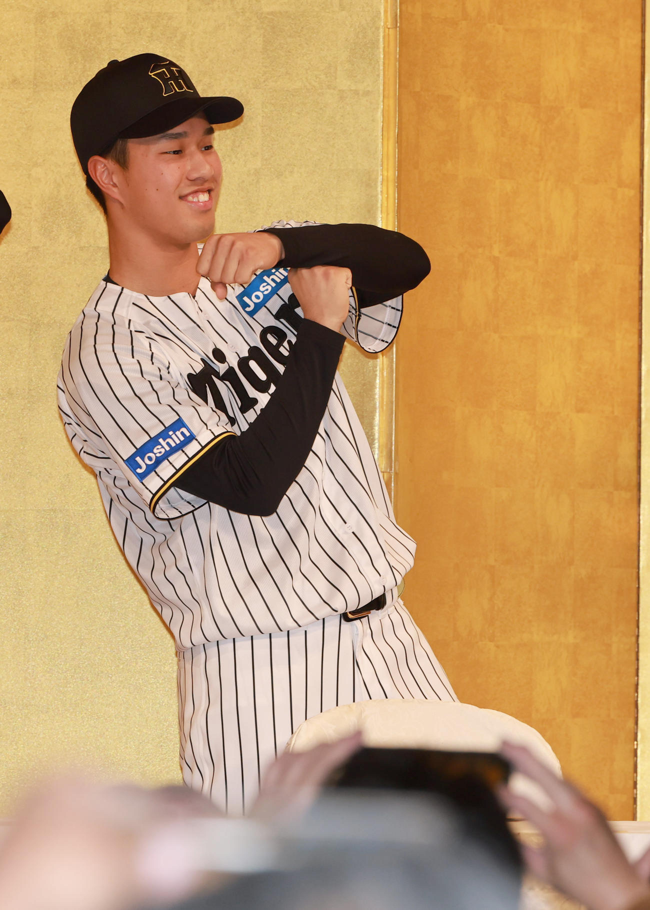 ファンミーティングの撮影会でTポーズを見せる岡城（撮影・上田博志）