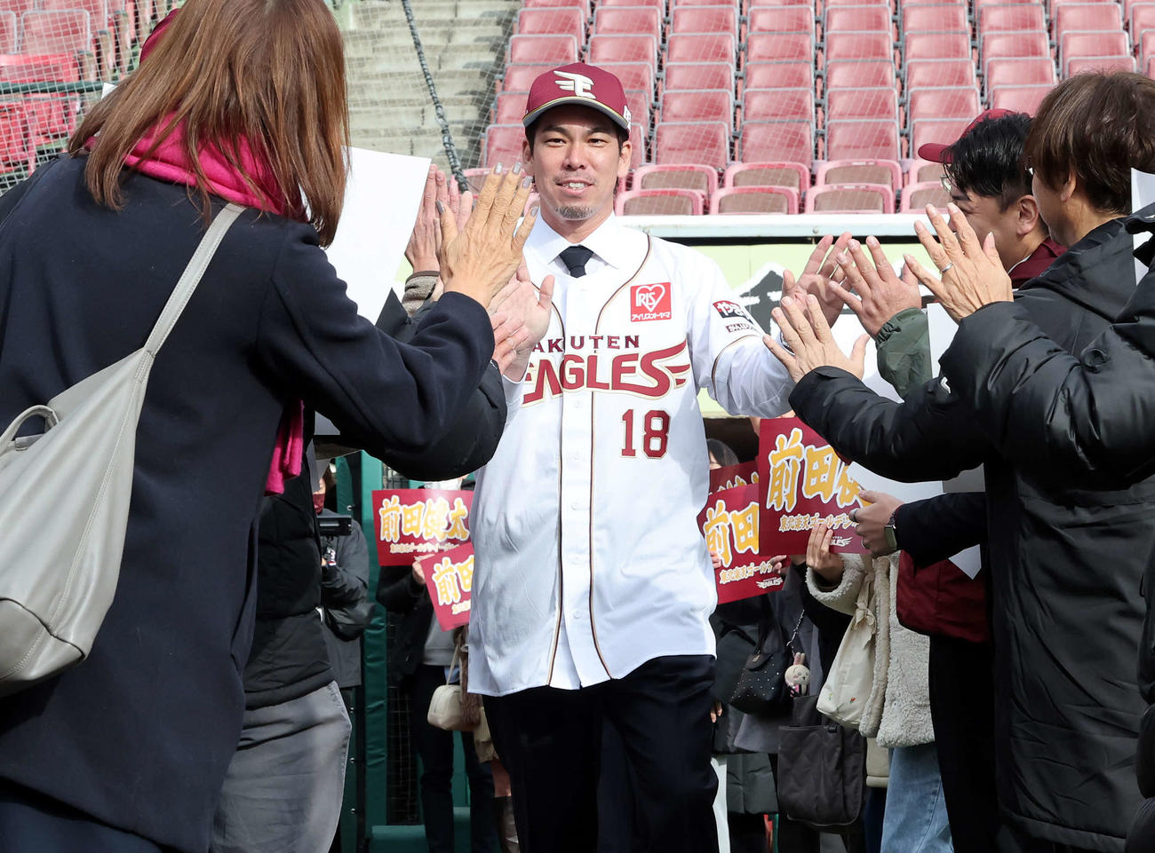 楽天入団会見で、ファンとハイタッチしながらグラウンドに出る前田健（撮影・浅見桂子）