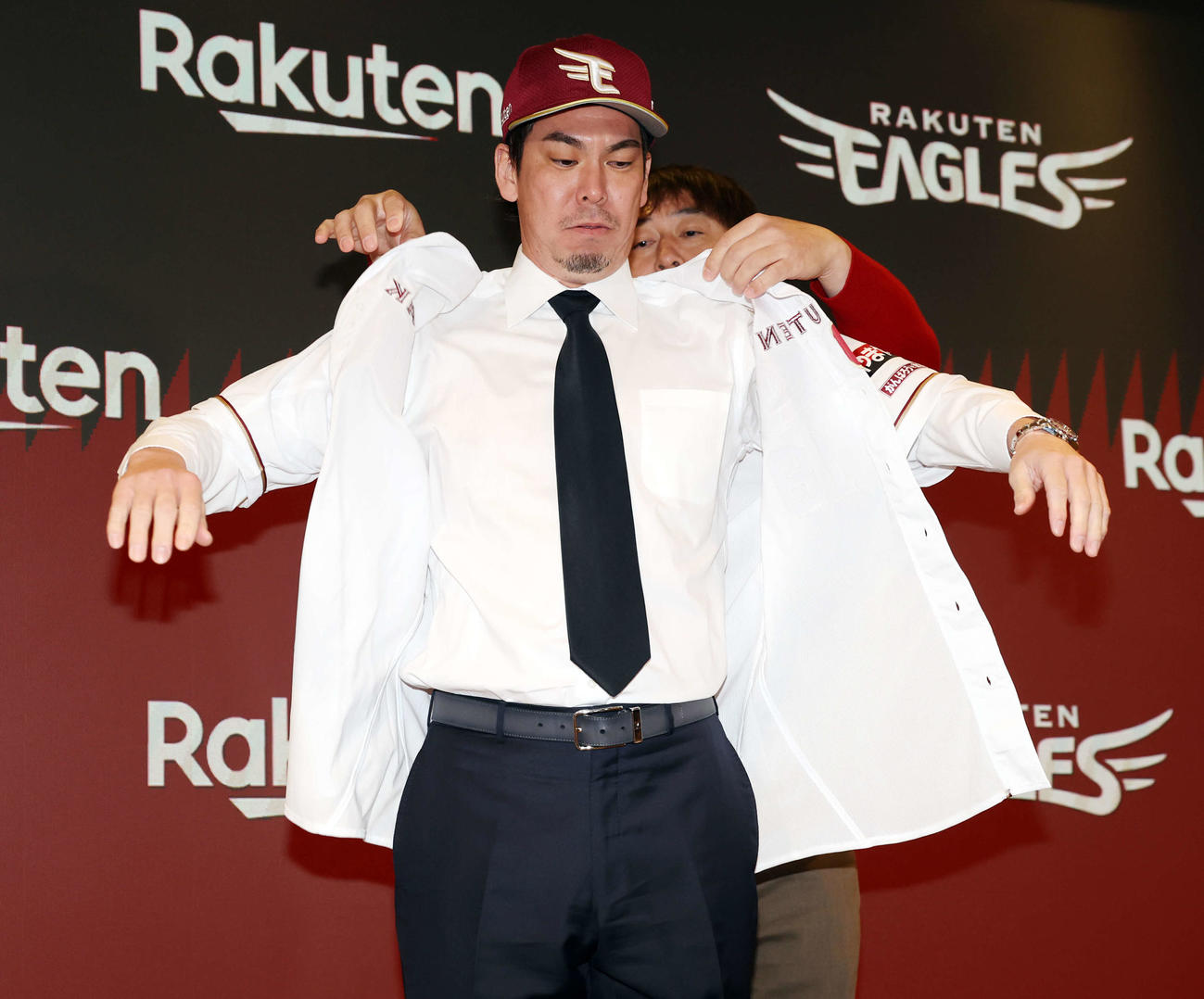 楽天入団会見に臨んだ前田健（左）は石井GMにユニホームを着せてもらう（撮影・浅見桂子）