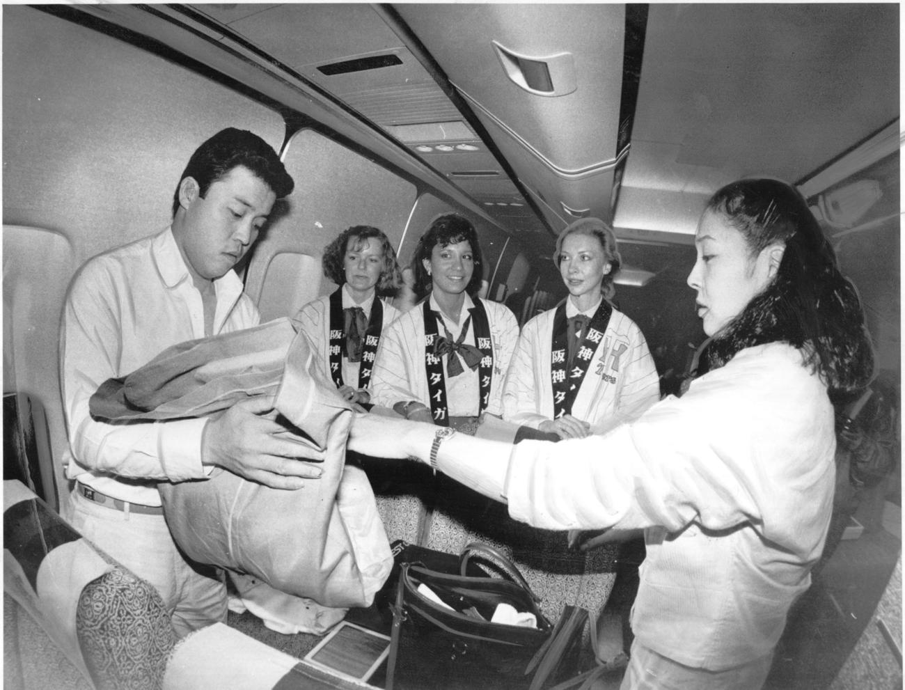 1985年12月、V旅行に向かう阪神・岡田彰布（左）。ノースウエスト航空のスチュワーデスもタイガースのはっぴを着て大サービス