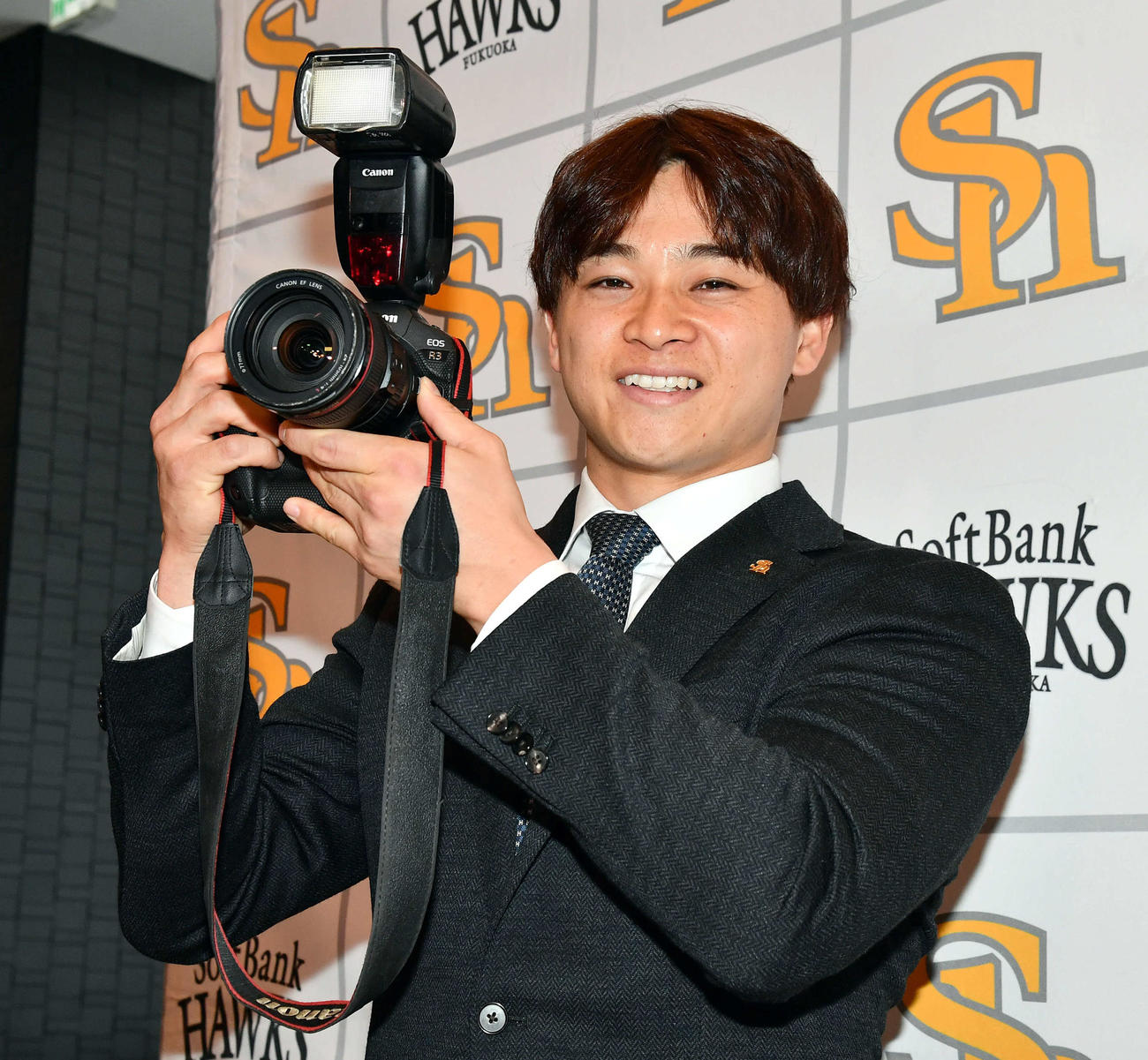 契約更改したソフトバンク谷川原は昇給分で「子どもを撮影するカメラを購入したい」とし、報道陣からカメラを借りて笑顔でポーズ（撮影・岩下翔太）