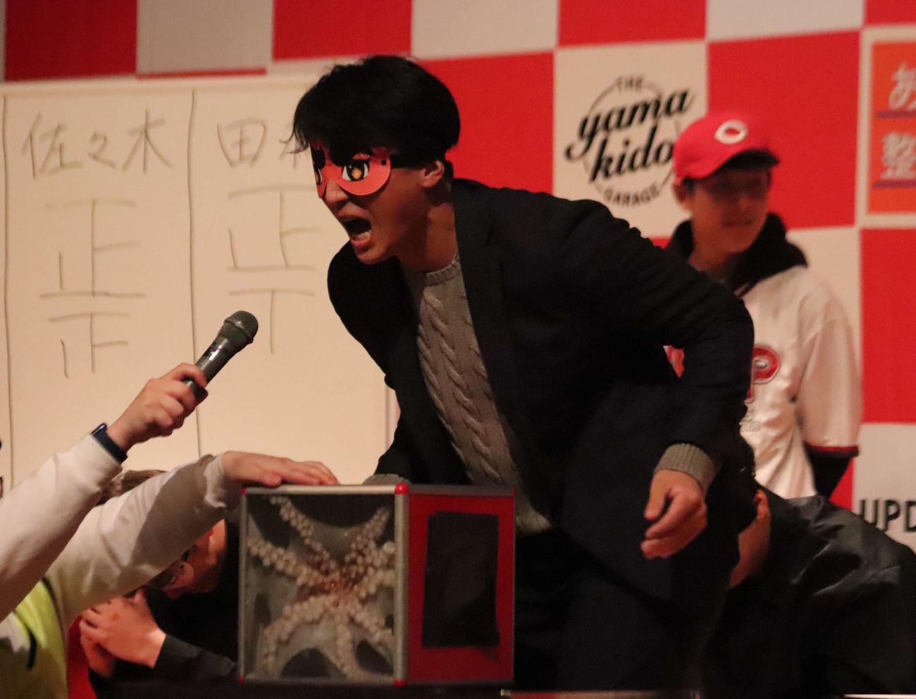 トークショーでアイマスクをして箱の中身（タコ）を当てるゲームに挑戦する広島佐々木泰内野手（撮影・前原淳）＝2025年12月20日、広島市内