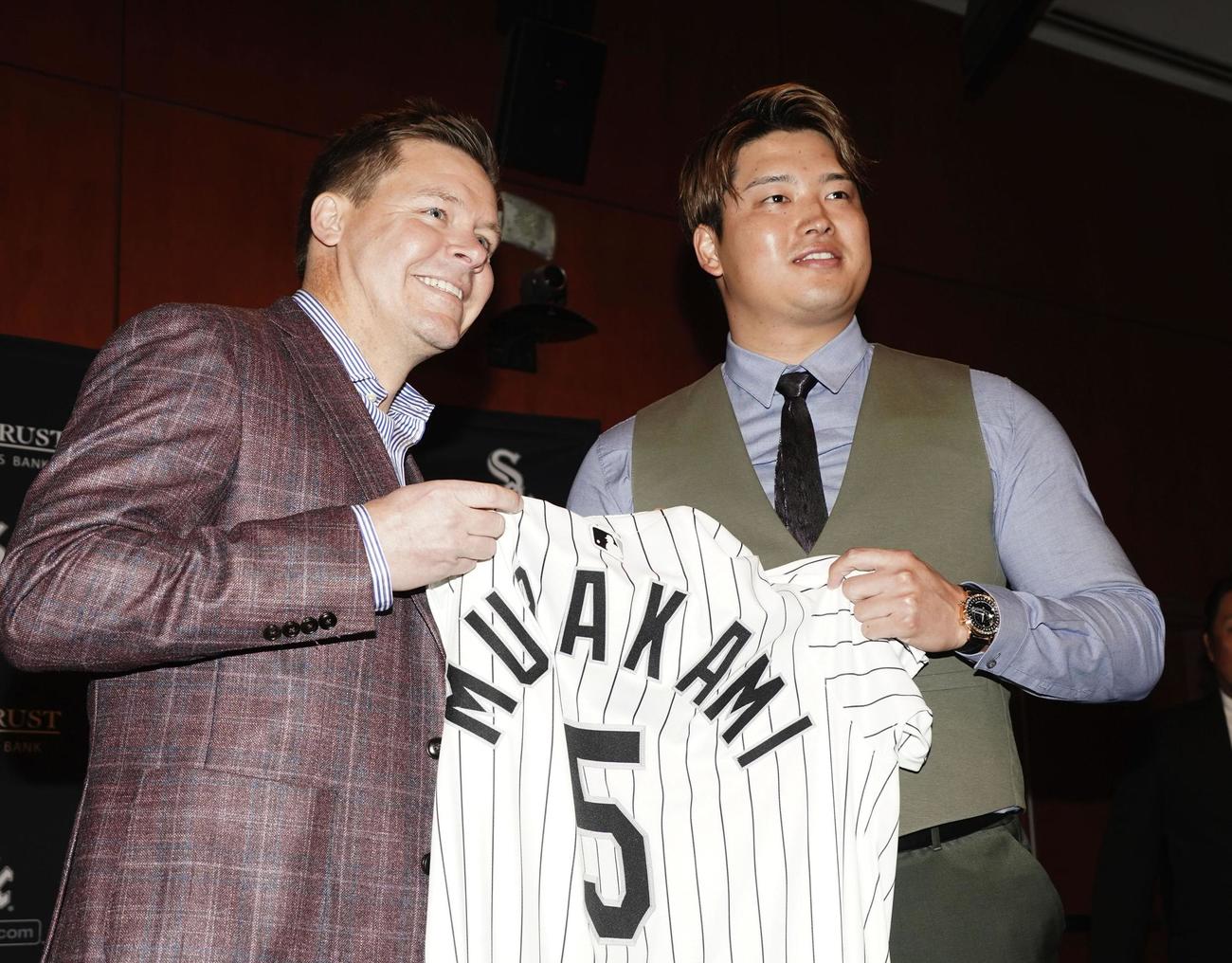 米大リーグ、ホワイトソックスの入団記者会見でユニホームを手にする村上宗隆。左はゲッツ・ゼネラルマネジャー（共同）