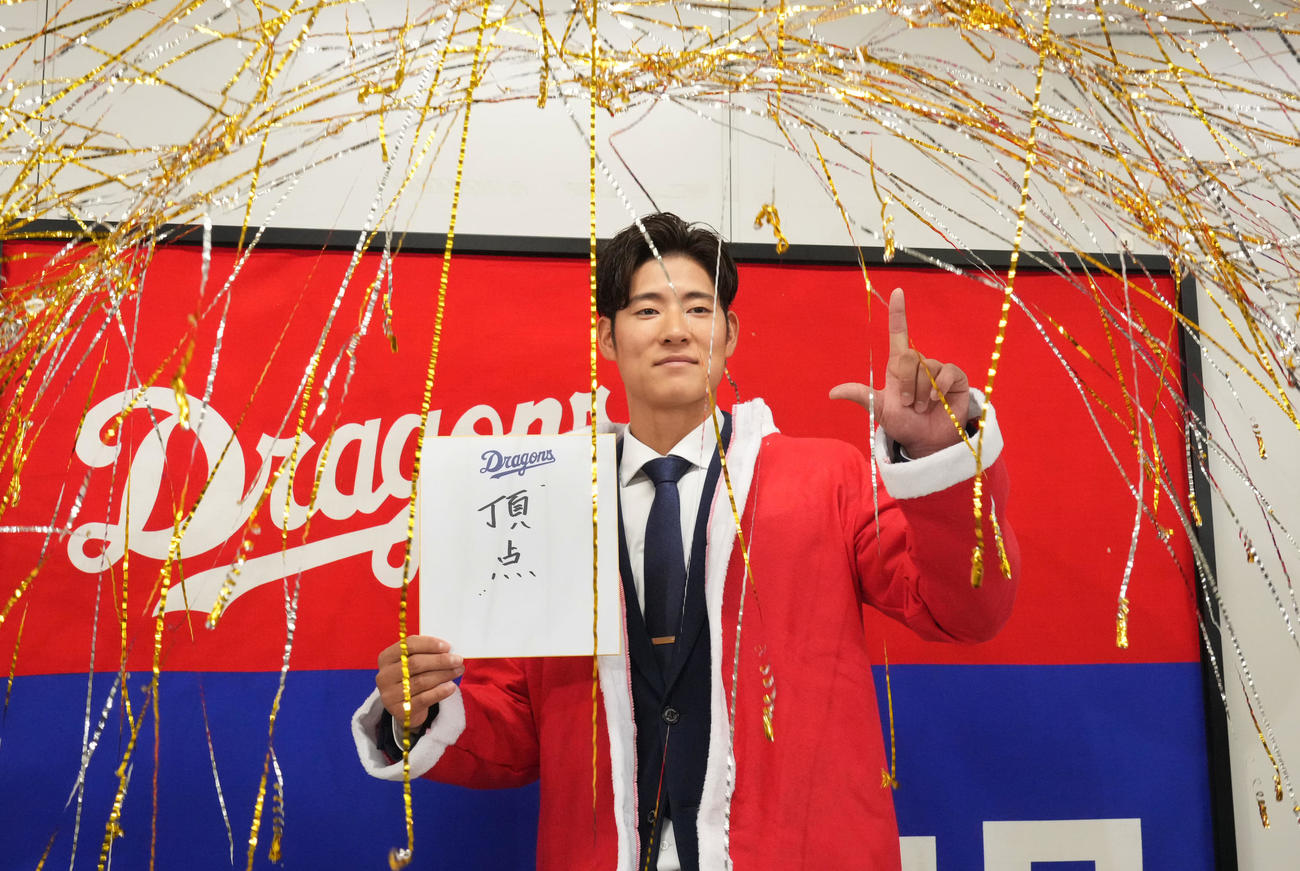 交渉を終え会見後、色紙に「頂点」と記しポーズを決める上林（撮影・森本幸一）