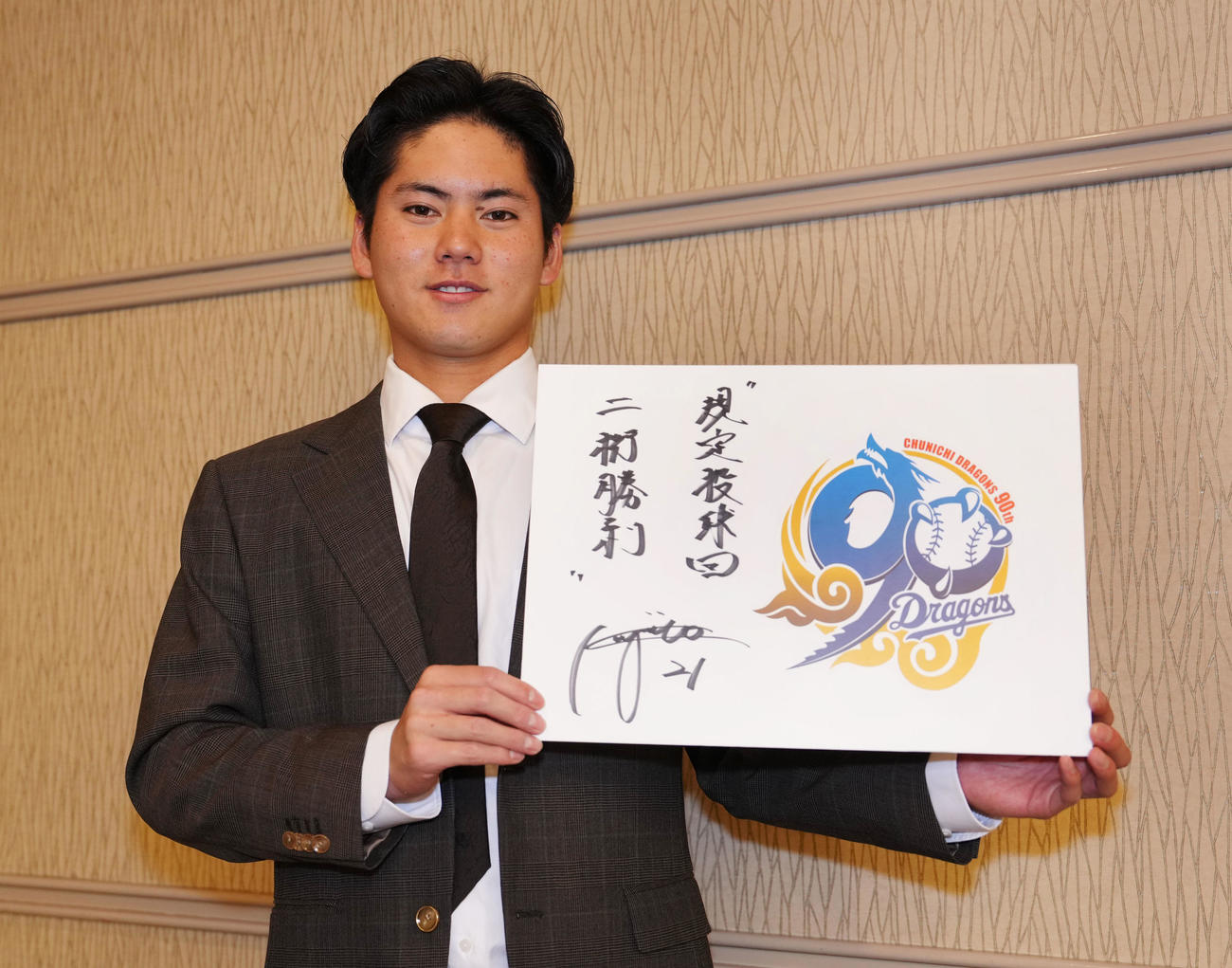 球団創立90周年記念ロゴパネルに来季の目標を掲げポーズを決める金丸夢斗