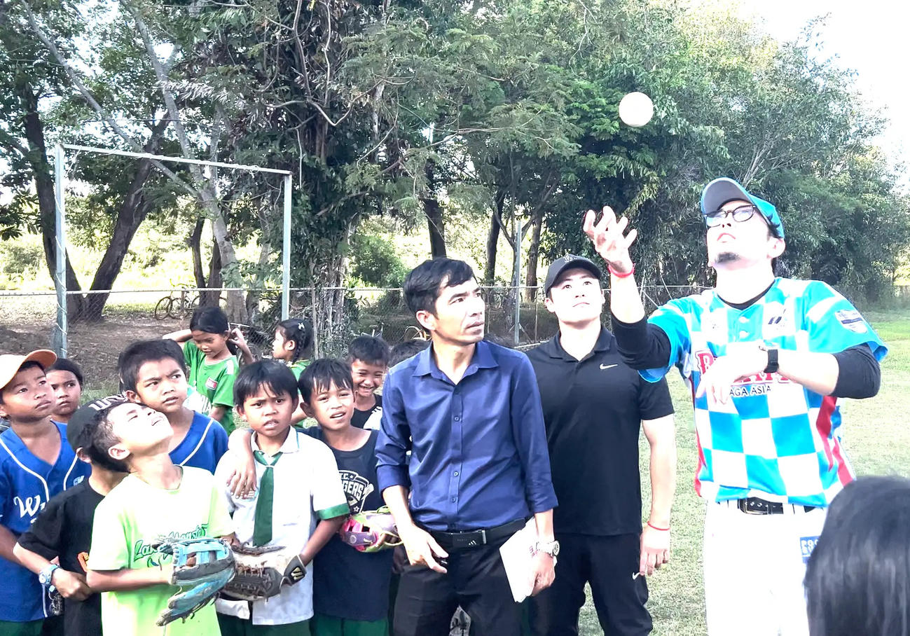 カンボジアで子どもたちに野球を教える佐賀アジアドリームズの香月監督（右）（佐賀アジアドリームズ提供）
