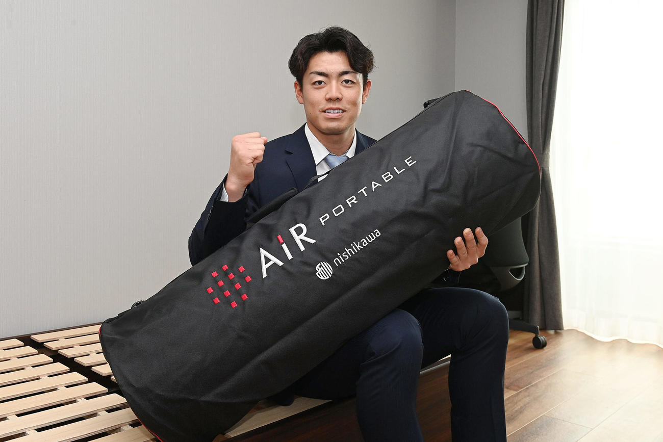 入寮で持ち込んだマットレスを手に笑顔を見せる阪神ドラフト2位の谷端