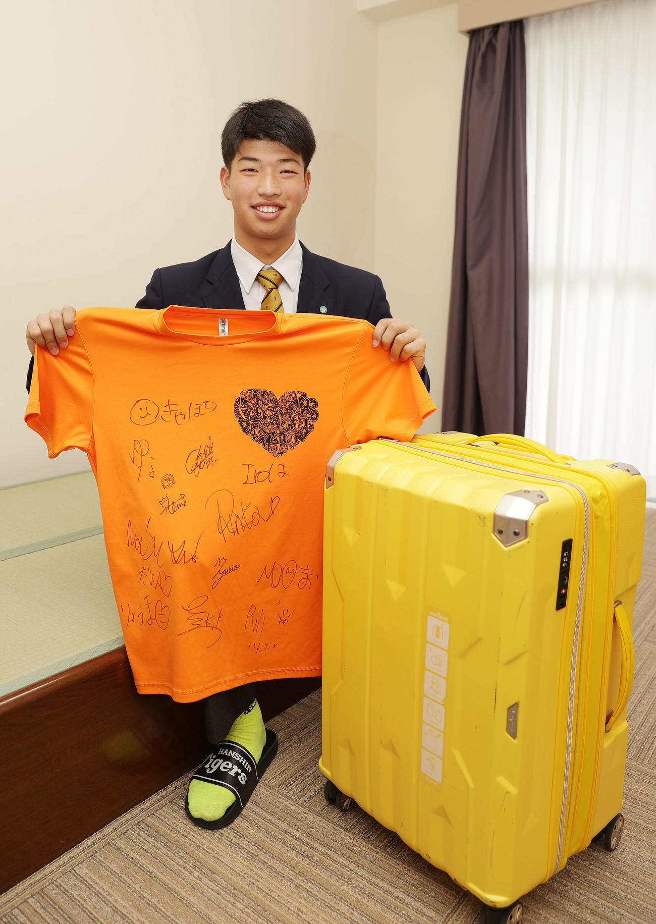 入寮でクラスメートのサインが書かれたTシャツを手に笑顔を見せる阪神百崎（24年1月撮影）