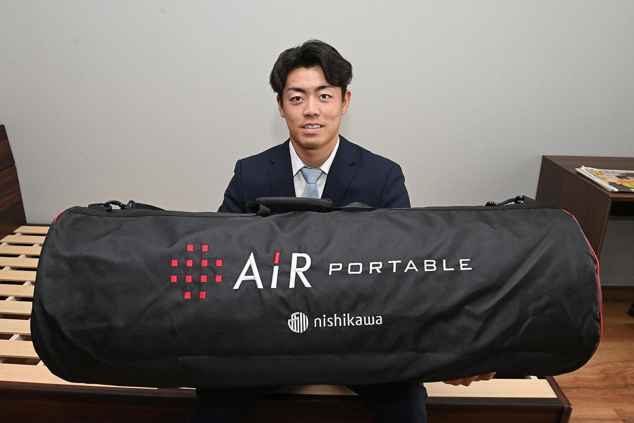 入寮で持ち込んだマットレスを手に笑顔を見せる阪神ドラフト2位の谷端