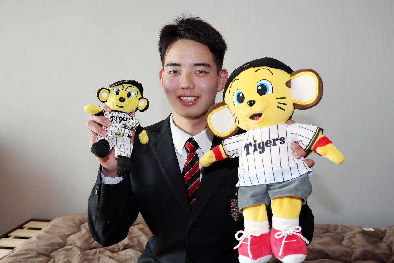 入寮で持ち込んだトラッキーとキー太のぬいぐるみを手に笑顔を見せる阪神ドラフト4位の早瀬（撮影・前田充）