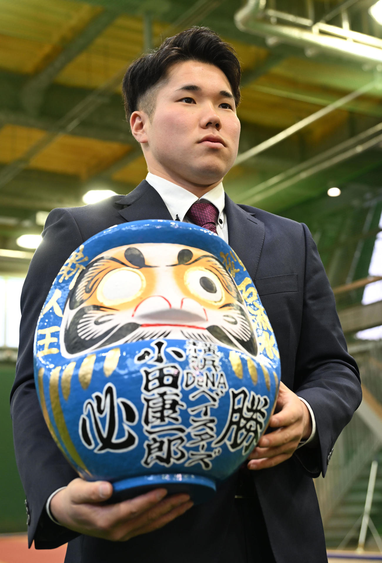 DeNAの選手寮に入寮し、持参しただるまを手に取材に応じるドラフト1位の小田康（撮影・千葉一成）