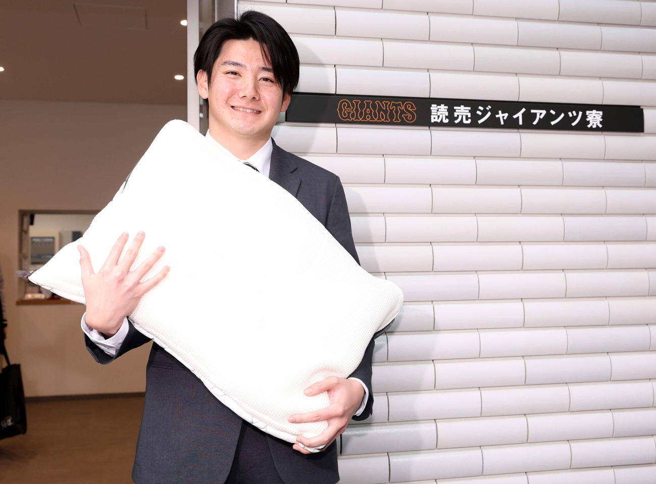 入寮した巨人ドラフト1位の竹丸は持参した枕を抱きかかえ笑顔（撮影・浅見桂子）