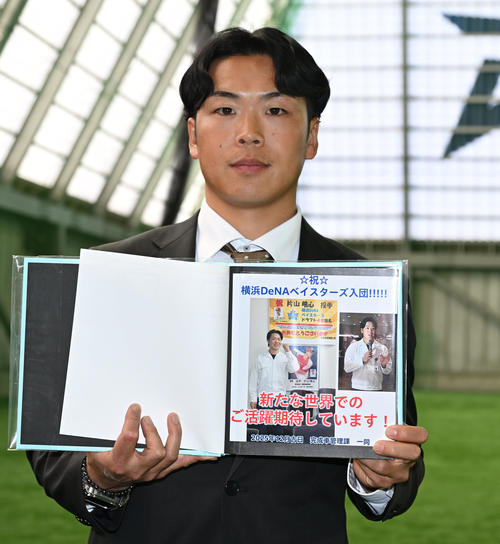 DeNAの選手寮に入寮し、前職場のホンダの仲間から贈られたアルバムを披露するドラフト4位の片山（撮影・千葉一成）