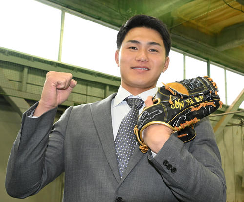 DeNAの選手寮に入寮し、NTT西日本の河本監督の名前が入ったグラブを手にポーズをとるドラフト5位の成瀬（撮影・千葉一成）