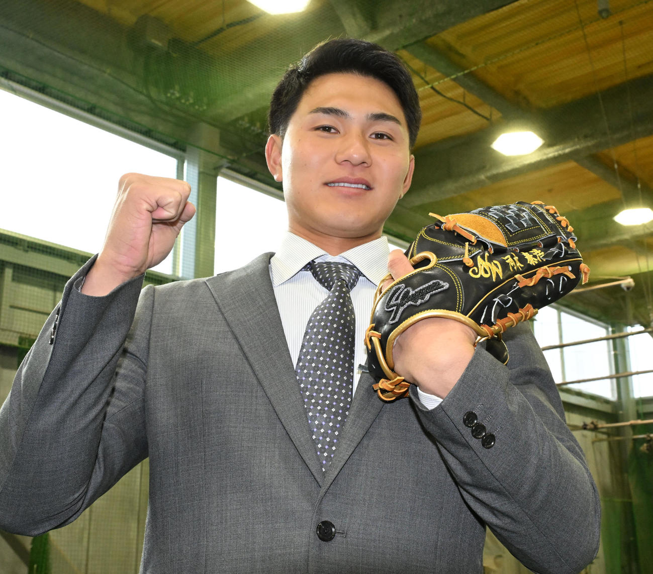 DeNAの選手寮に入寮し、NTT西日本の河本監督の名前が入ったグラブを手にポーズをとるドラフト5位の成瀬（撮影・千葉一成）