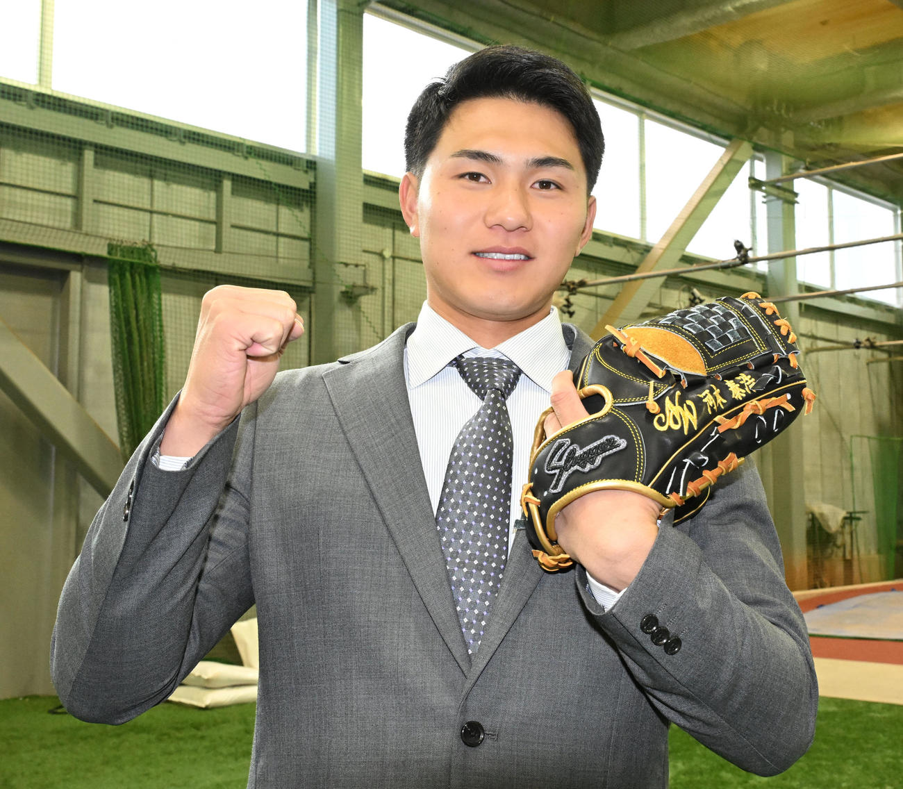 DeNAの選手寮に入寮し、NTT西日本の河本監督の名前が入ったグラブを手にポーズをとるドラフト5位の成瀬（撮影・千葉一成）