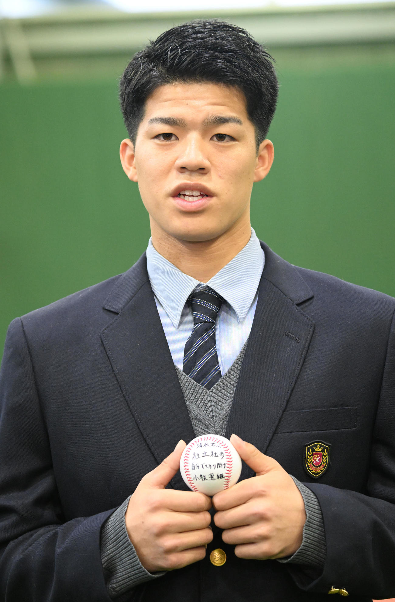 DeNAの選手寮に入寮し、京都国際高校野球部の小牧憲継監督から贈られたメッセージ入りのボールを手に取材に応じる育成1位の清水（撮影・千葉一成）