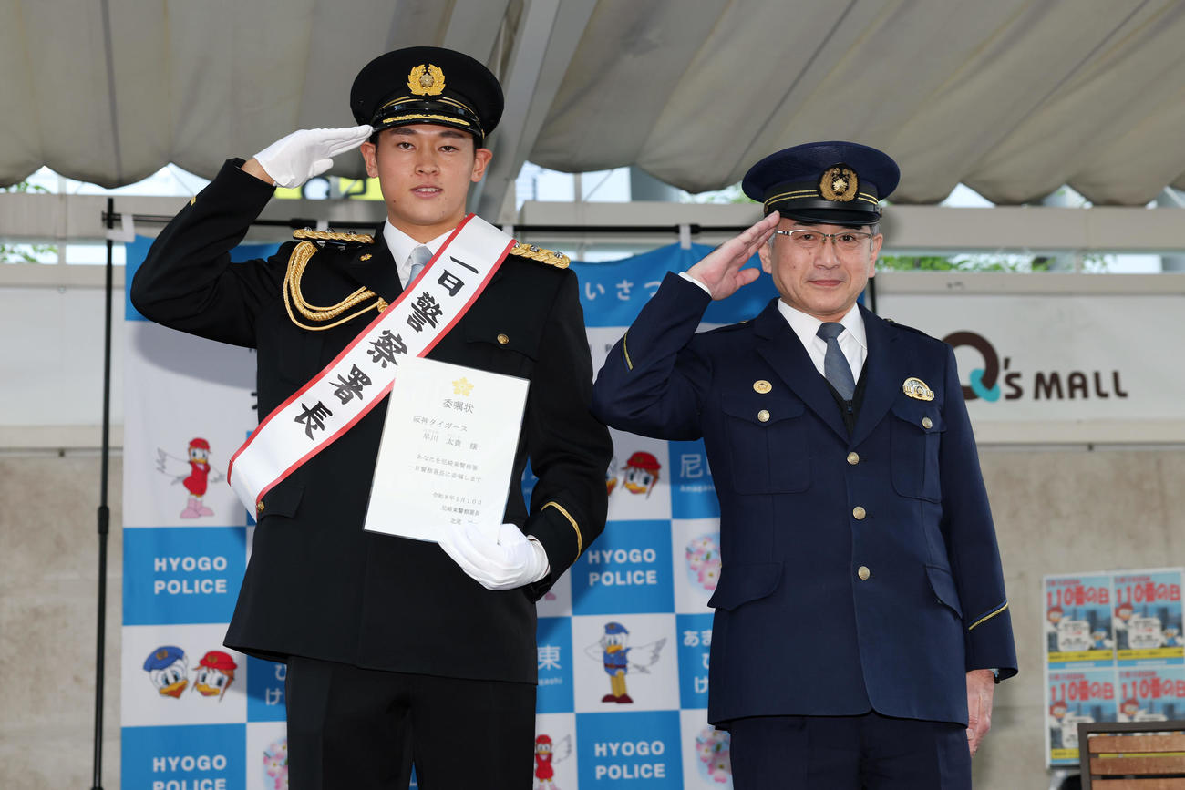 尼崎東警察署の「一日警察署長」を委嘱され、敬礼ポーズをとる阪神早川太貴。右は北尾祐一尼崎東警察署長（撮影・前田充）