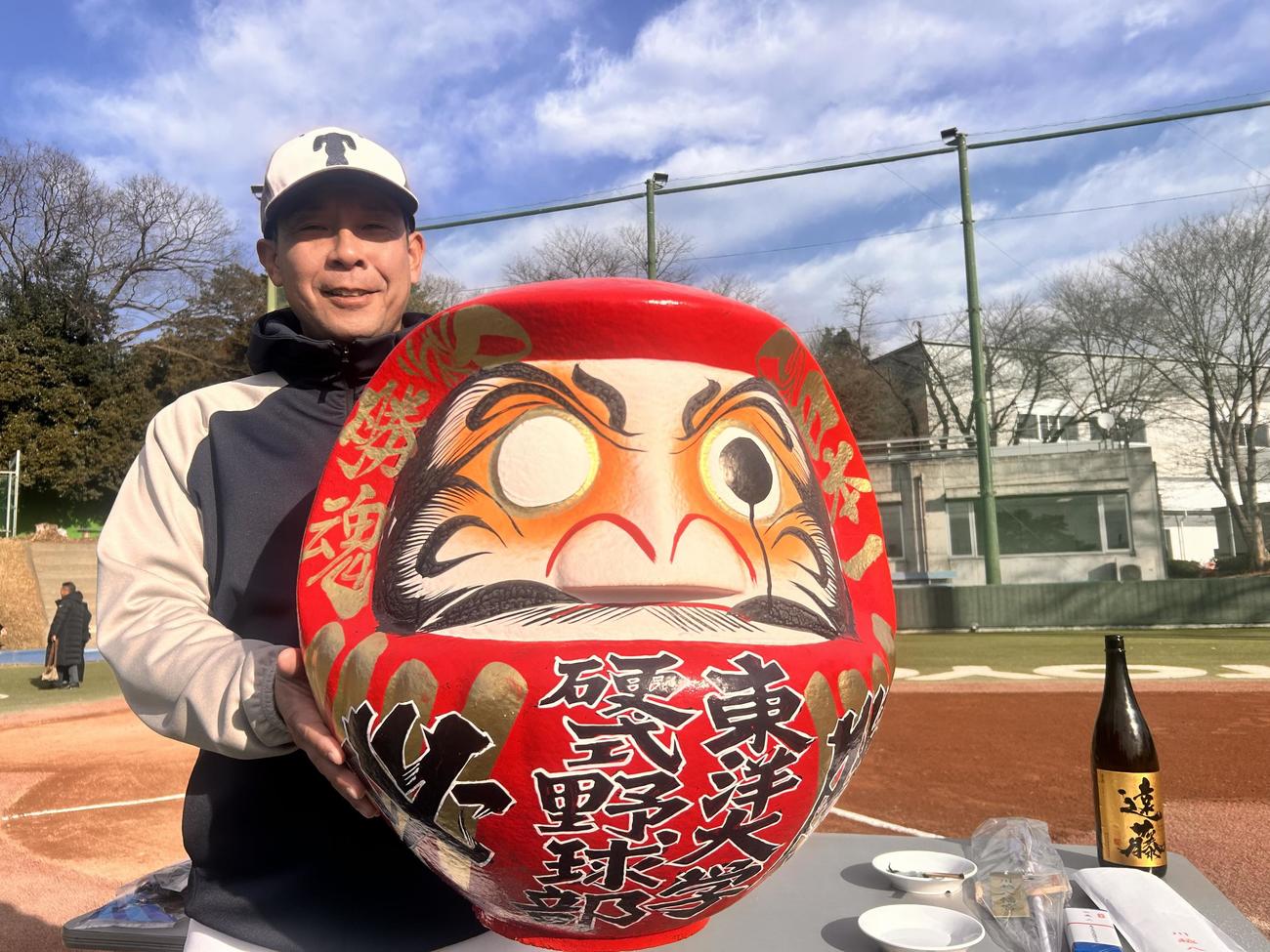 グラウンド開きで、目を入れたダルマを持つ東洋大・井上大監督（撮影・平山連）