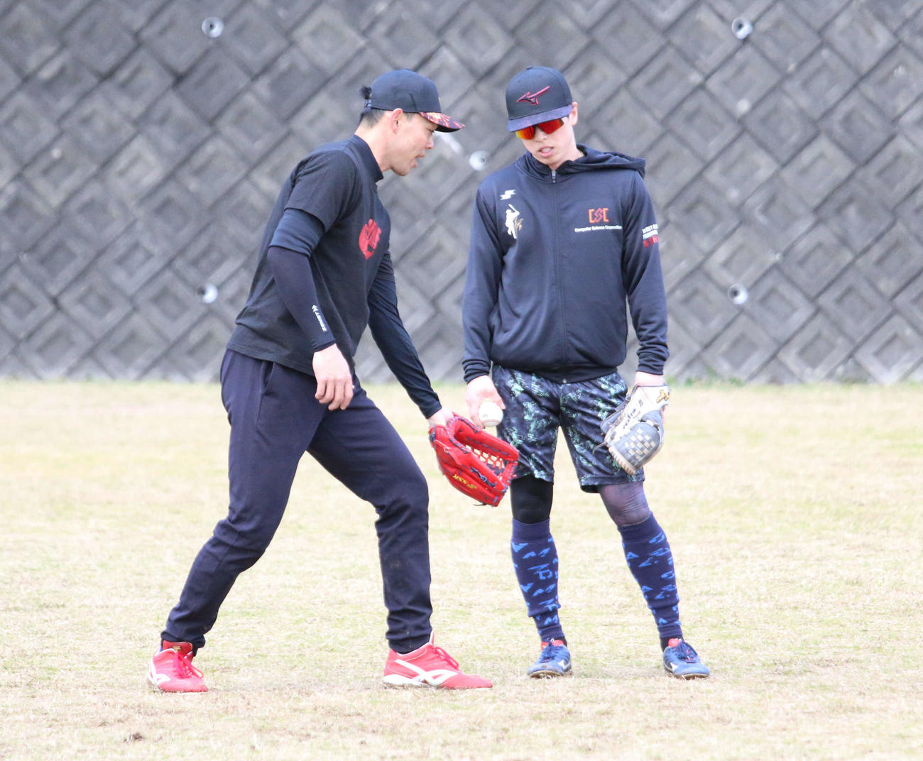 静岡・下田にある吉佐美運動公園で合同自主トレを行う広島秋山（左）からアドバイスを受ける日本ハム五十幡（撮影・木下大輔）