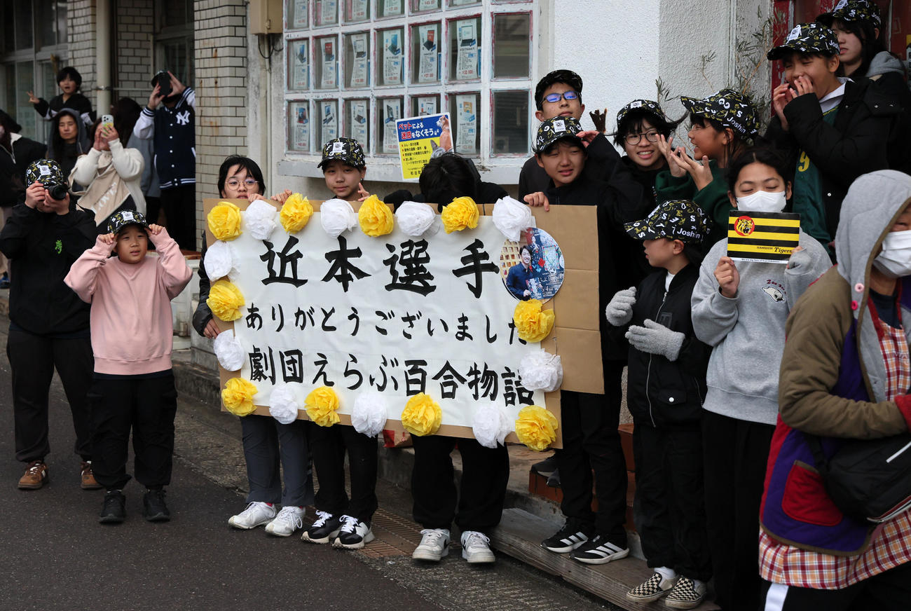 阪神近本の優勝記念イベントでパレード車両に向かってボードを掲出する地元の人たち（撮影・加藤哉）