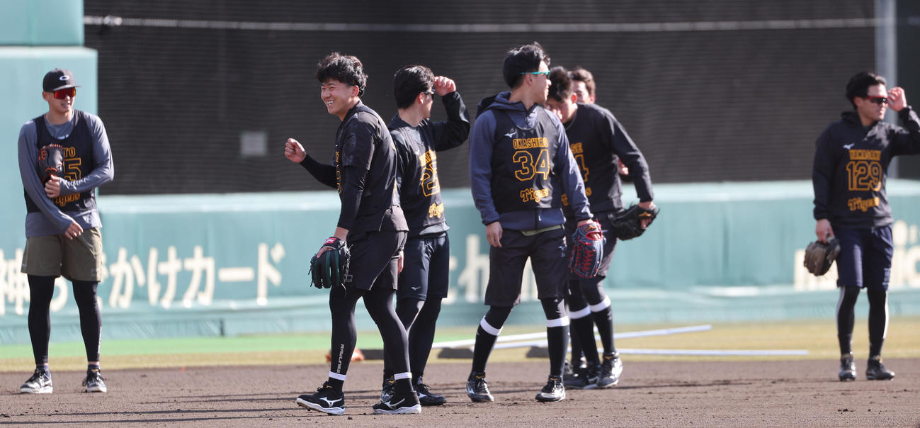 新人合同自主トレで強い風に砂ぼこりがまい練習が一時中断、苦笑いする阪神立石（中央）（撮影・西尾就之）