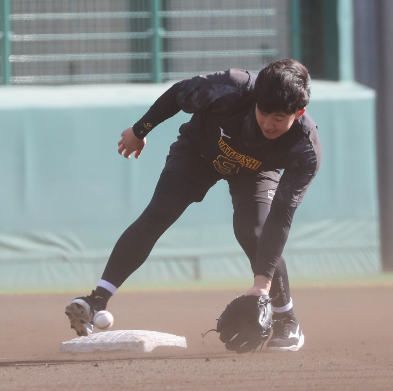 新人合同自主トレで強い風に砂ぼこりがまう中、ノックを受ける阪神立石（中央）（撮影・西尾就之）