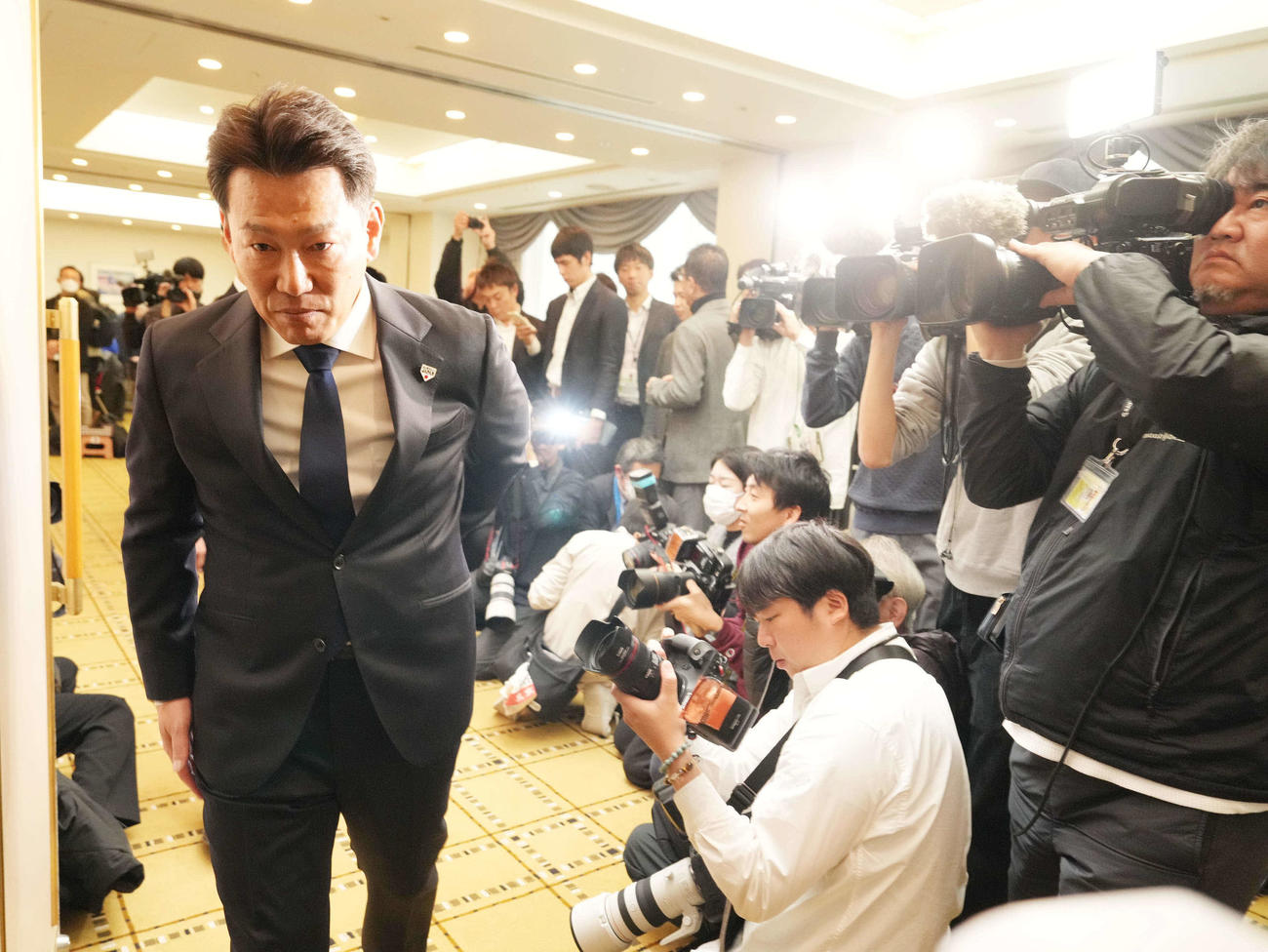 2026WBC侍ジャパン出場予定選手を発表し大勢のカメラマンに囲まれながら会場を引き揚げる井端監督（撮影・小沢裕）