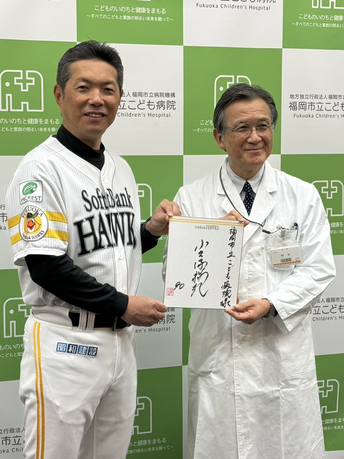 福岡市立こども病院を慰問に訪れたソフトバンク小久保監督（左）は楠原浩一院長に色紙を手渡す