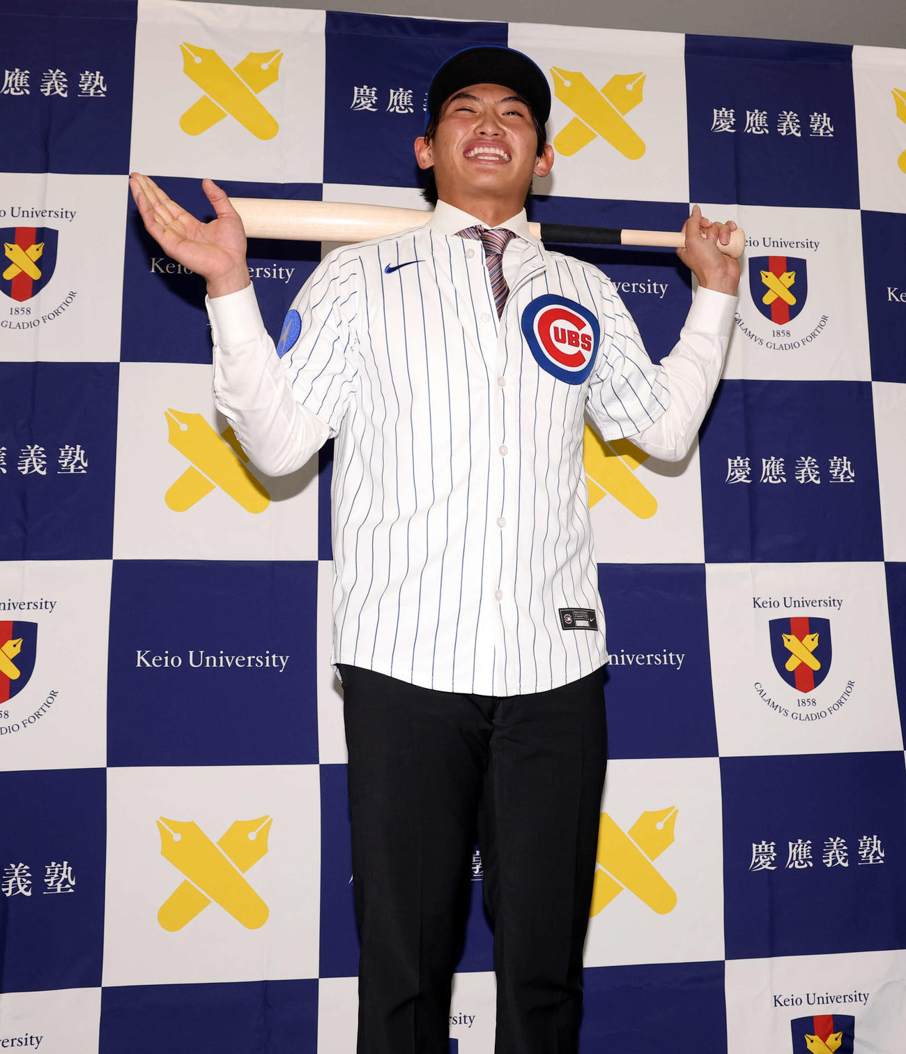 MLBのカブスとマイナー契約契約を結んだ慶大・常松はユニホームを着用し、報道陣からのポーズの要求に照れ笑いする（撮影・浅見桂子）