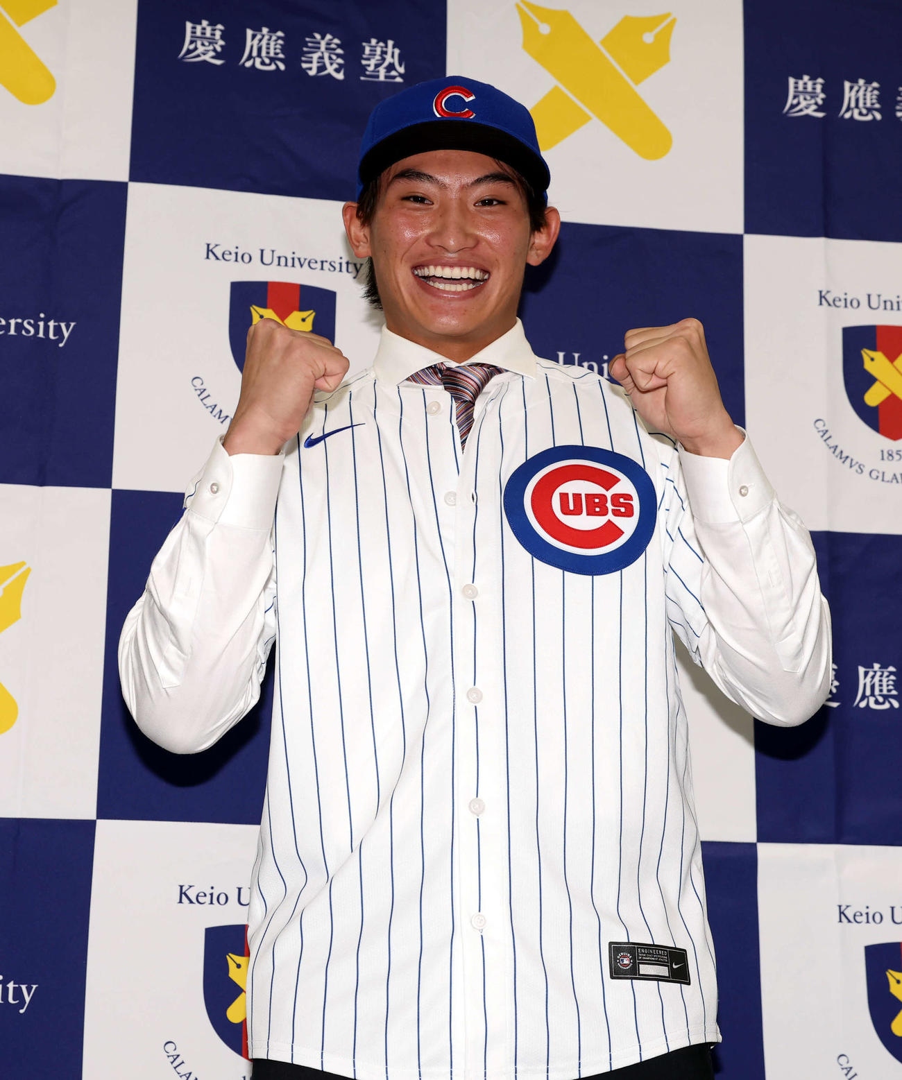 MLBのカブスとマイナー契約契約を結んだ慶大・常松はユニホームを着用し笑顔でガッツポーズ（撮影・浅見桂子）