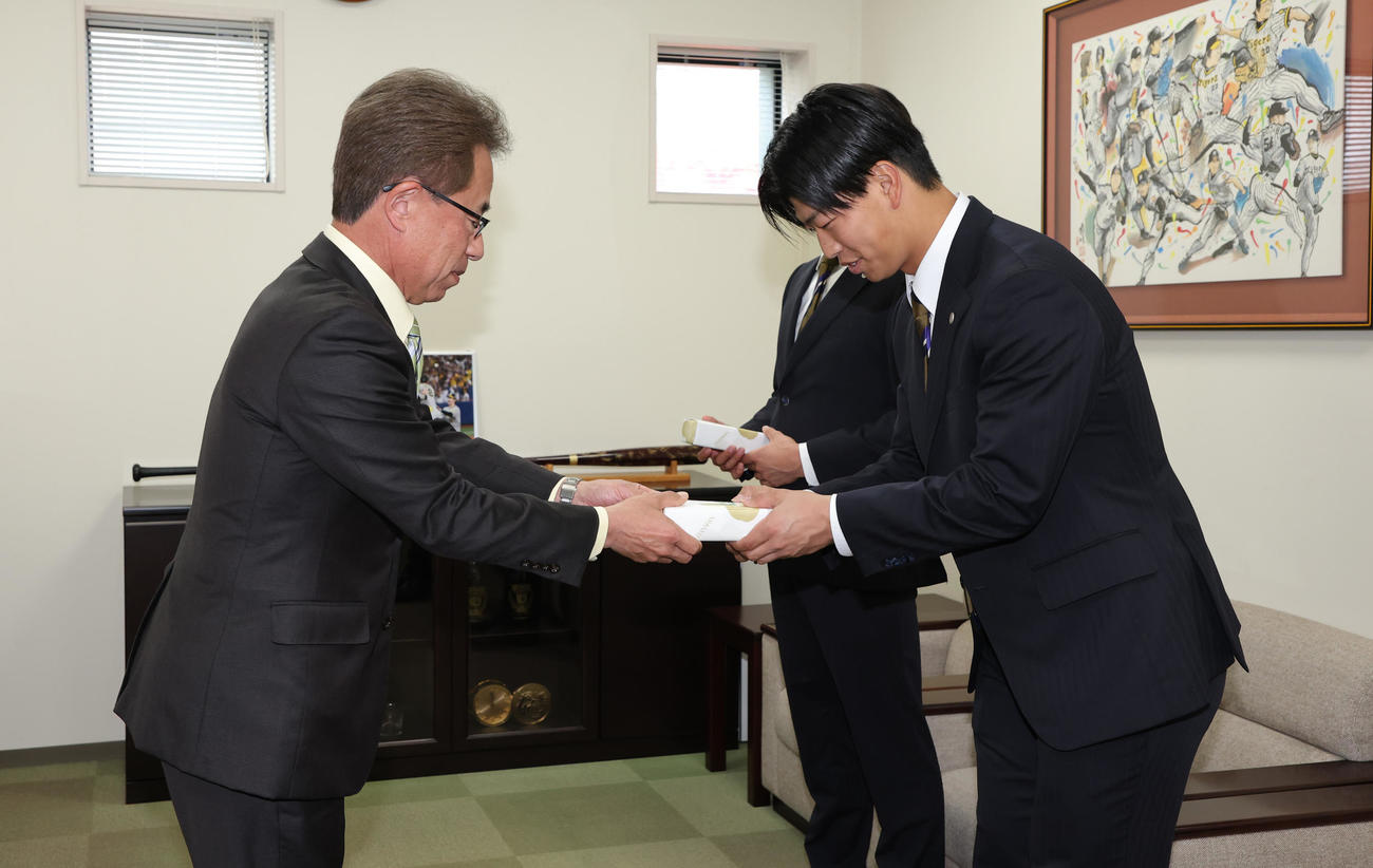 阪神の20歳記念品贈呈式で粟井社長（左）から記念品を受け取る百崎