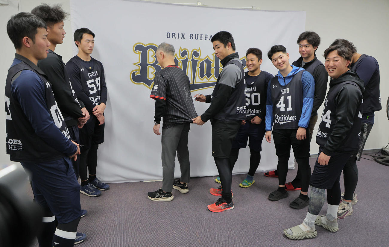 新人選手を対象に行われた「ファンサービスの大切さを伝える講習」を受けたオリックス藤川（中央右）は、講師を務めた中島事業推進部副部長が着用したユニホームにサインをする（撮影・宮崎幸一）