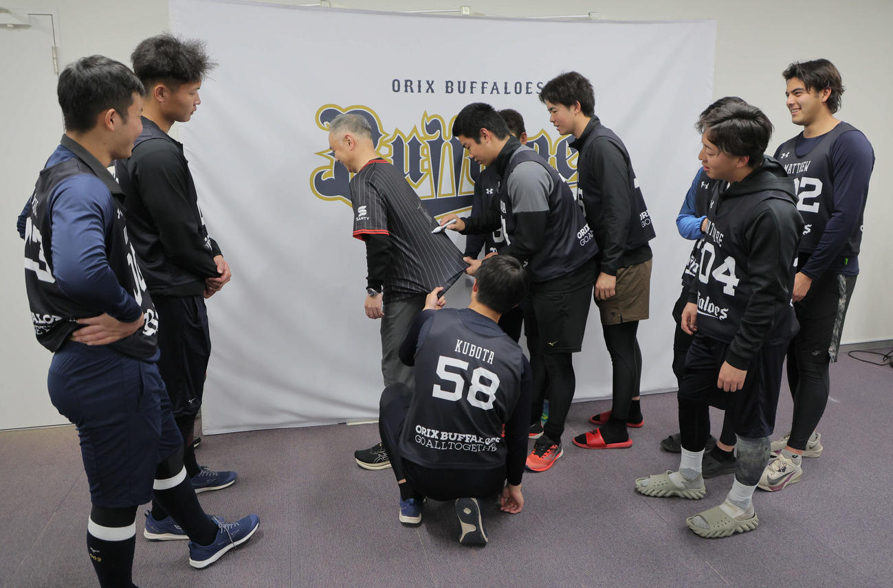 新人選手を対象に行われた「ファンサービスの大切さを伝える講習」を受けたオリックス藤川（中央右）は、講師を務めた中島事業推進部副部長が着用したユニホームを伸ばしてサインする（撮影・宮崎幸一）