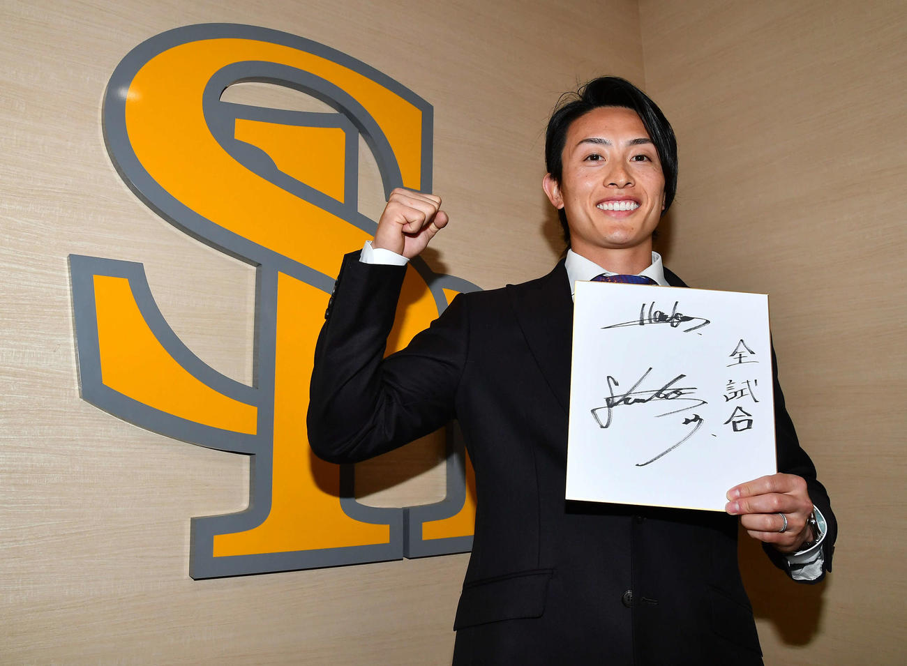 複数年の大型契約を結んだソフトバンク周東は、色紙に今季の目標を「全試合」と記してガッツポーズする（撮影・岩下翔太）