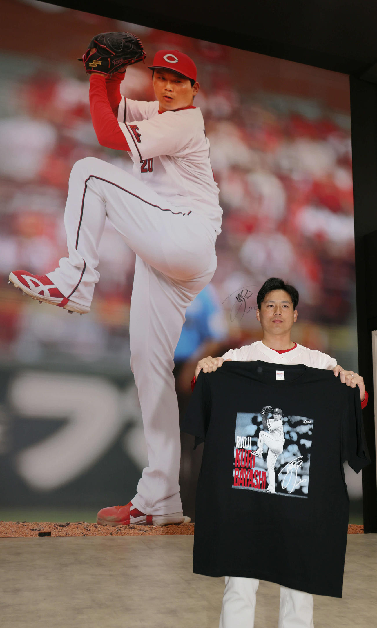 球場正面グッズ売り場の壁面に登場した巨大写真の前でポーズを決める広島栗林（撮影・加藤孝規）