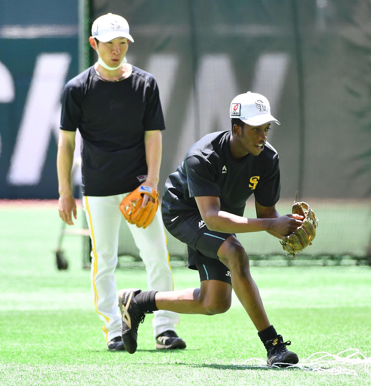 ソフトバンク対日本ハム　アーリーワークで本多雄一内野守備走塁兼作戦コーチ（左）から指導を受けながらノックを受けるイヒネ・イツア（撮影・岩下翔太）＝2025年5月27日、みずほペイペイドーム
