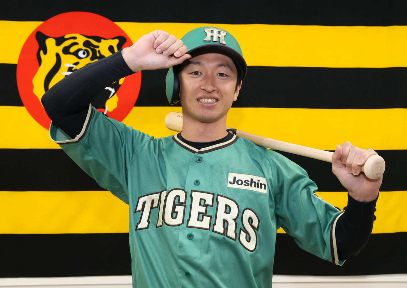 阪神近本がスタジアムヒーロズデーユニホームのお披露目会見を行い、バットをかかえて写真に納まる（撮影・加藤哉）