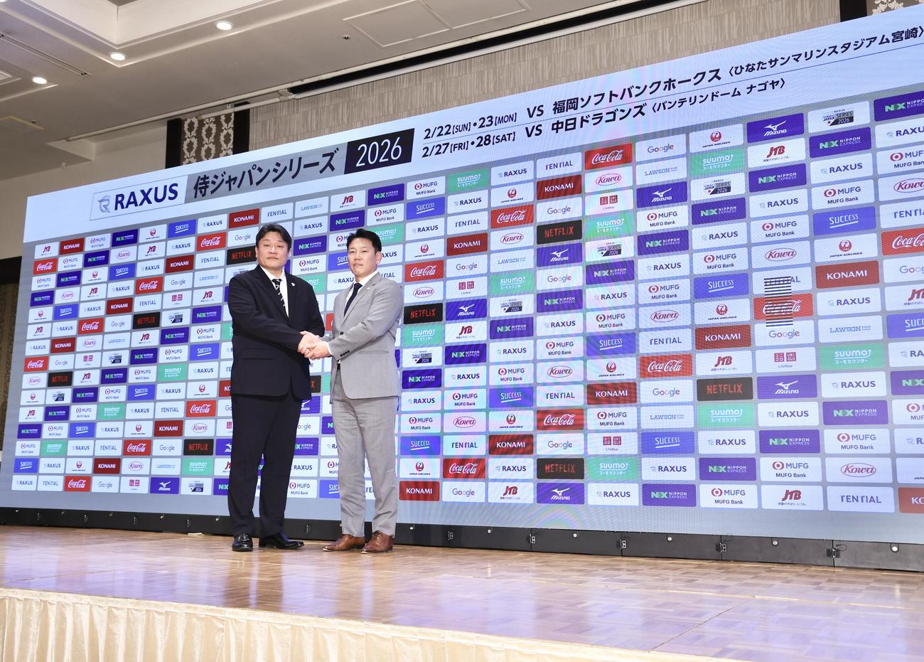 握手を交わしながら写真に納まる中村事務局長（左）と井端監督（撮影・河田真司）