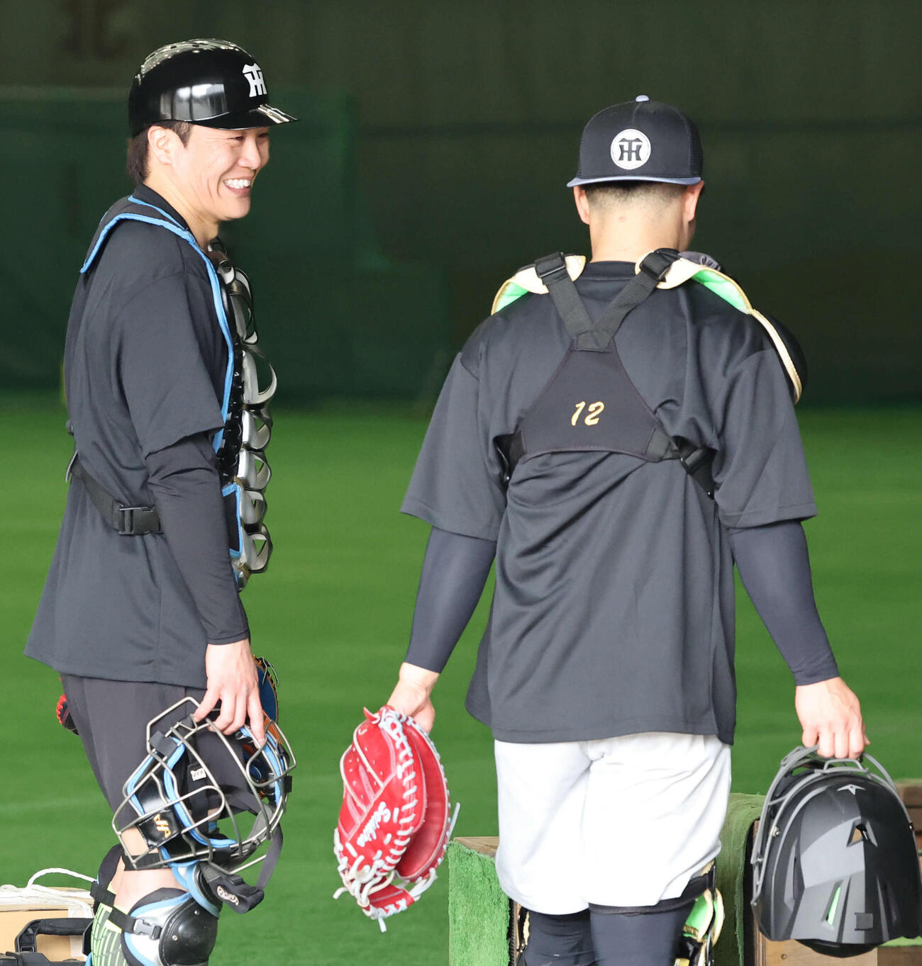 ブルペンでの捕球を終えた伏見（左）は坂本と話す（撮影・西尾就之）