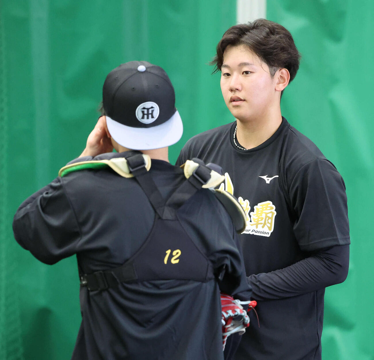 ブルペンで投げ終えた阪神門別（右）は受けた坂本と話す（撮影・西尾就之）